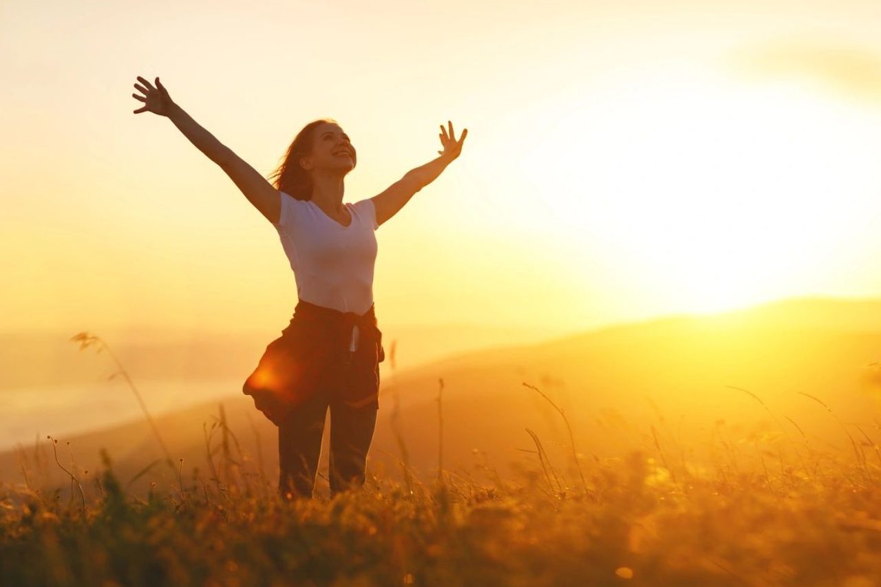 A woman standing in the middle of a field with her arms outstretched.